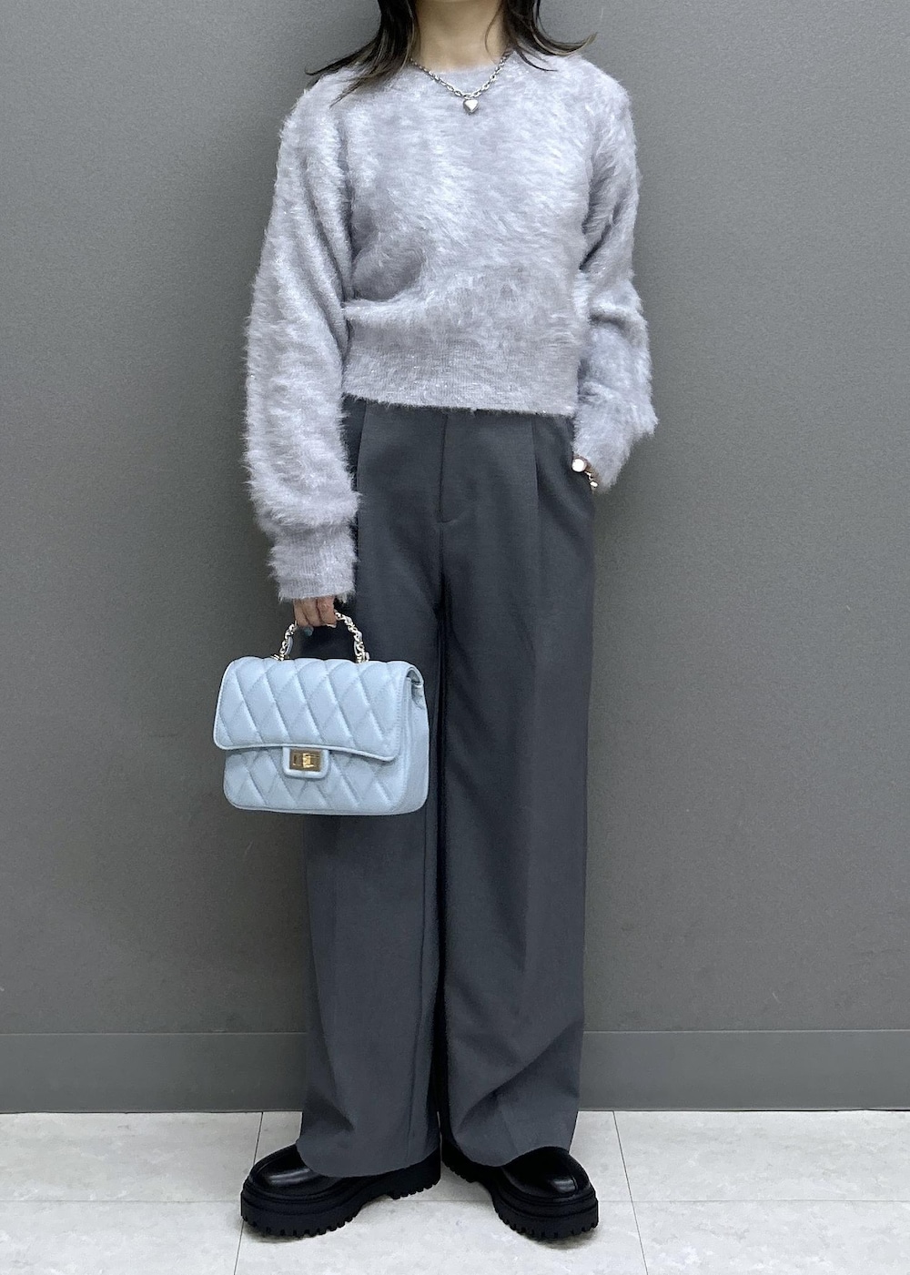 グレー系のスラックス、ブラック系のブーツ、ブラック系のチェスターコートを着用したレディースの秋コーディネートの8枚目の写真