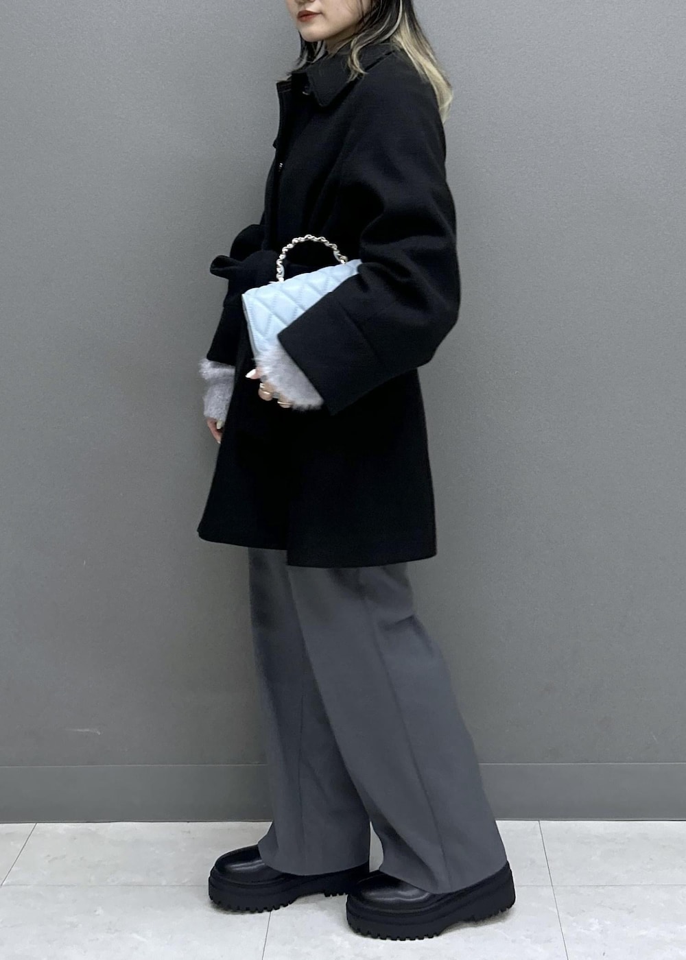 グレー系のスラックス、ブラック系のブーツ、ブラック系のチェスターコートを着用したレディースの秋コーディネートの3枚目の写真
