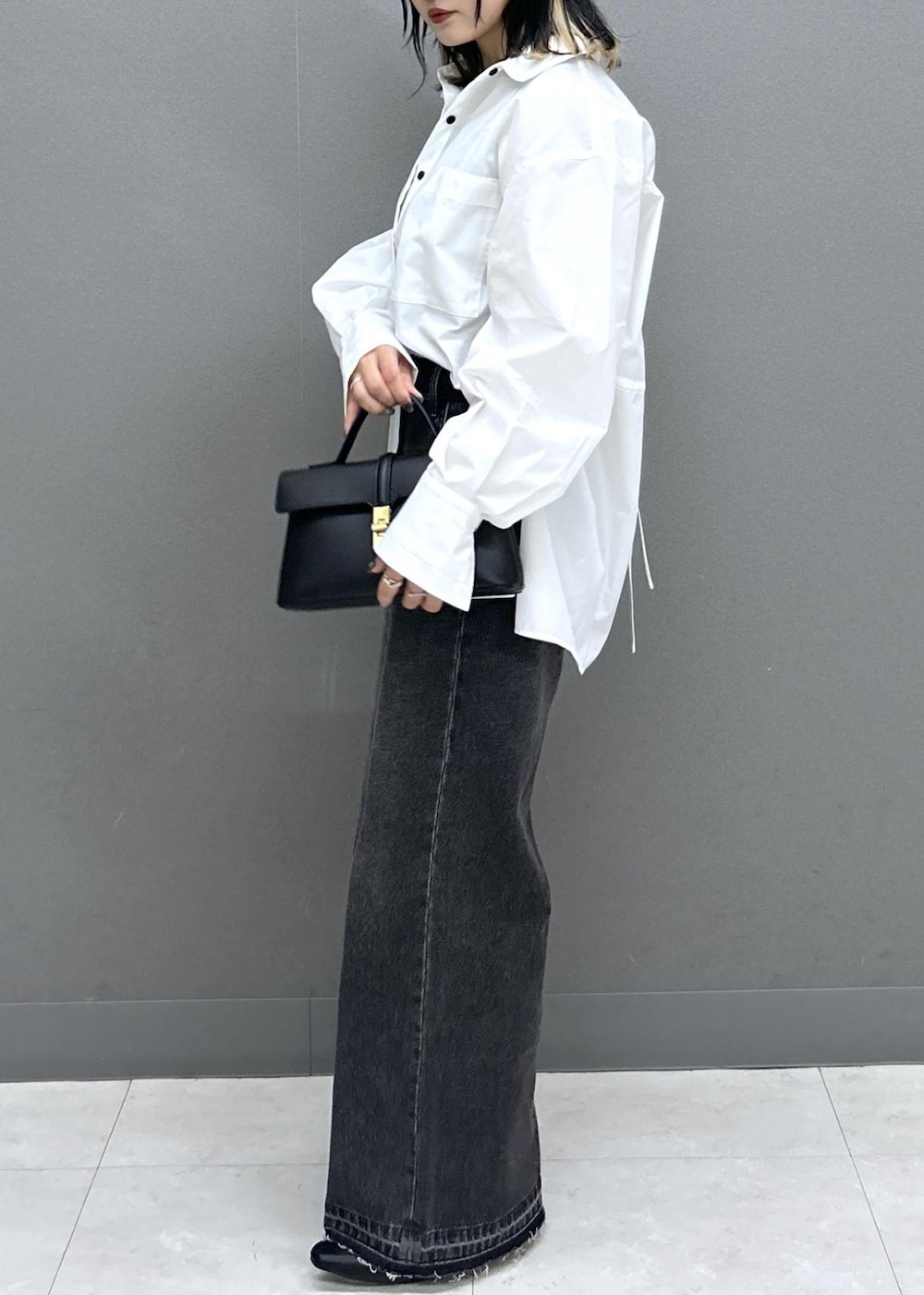 ブラック系のショルダーバッグ、ブラック系のパンプス、ブラック系のデニムパンツを着用したレディースの春コーディネートの4枚目の写真