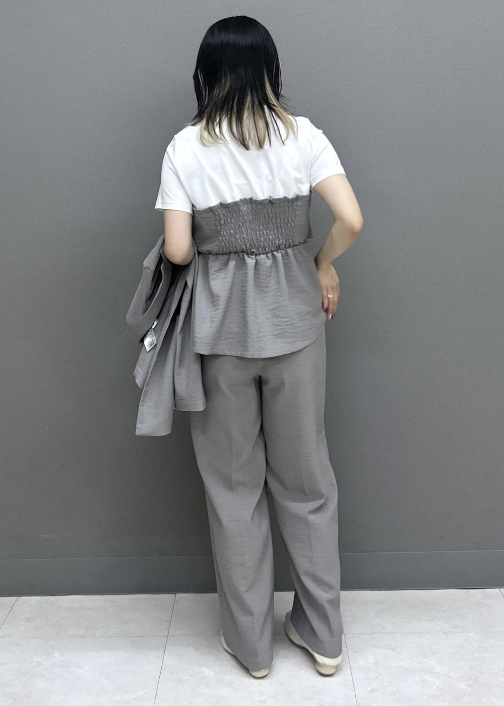 ベージュ系のショルダーバッグ、ホワイト系のパンプス、グレー系のTシャツ/カットソーを着用したレディースの夏コーディネートの2枚目の写真