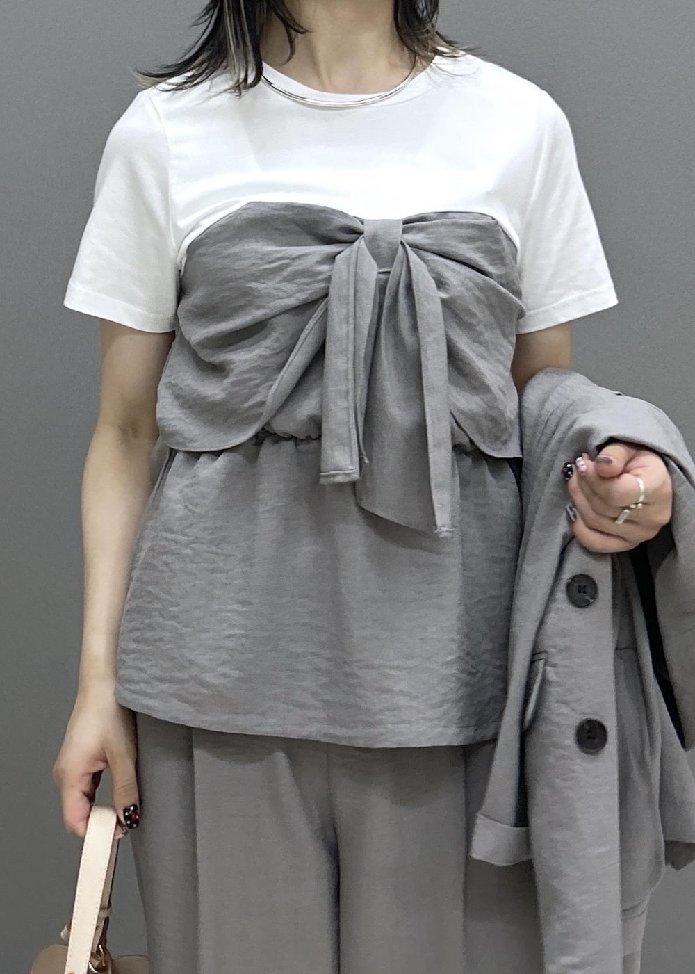 ベージュ系のショルダーバッグ、ホワイト系のパンプス、グレー系のTシャツ/カットソーを着用したレディースの夏コーディネートの3枚目の写真