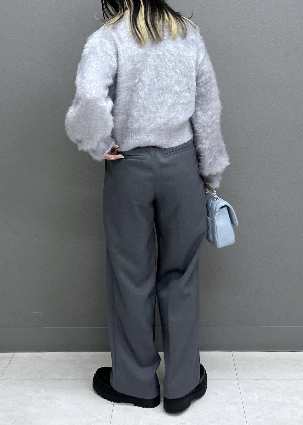 グレー系のスラックス、ブラック系のブーツ、ブラック系のチェスターコートを着用したレディースの秋コーディネートの10枚目の写真