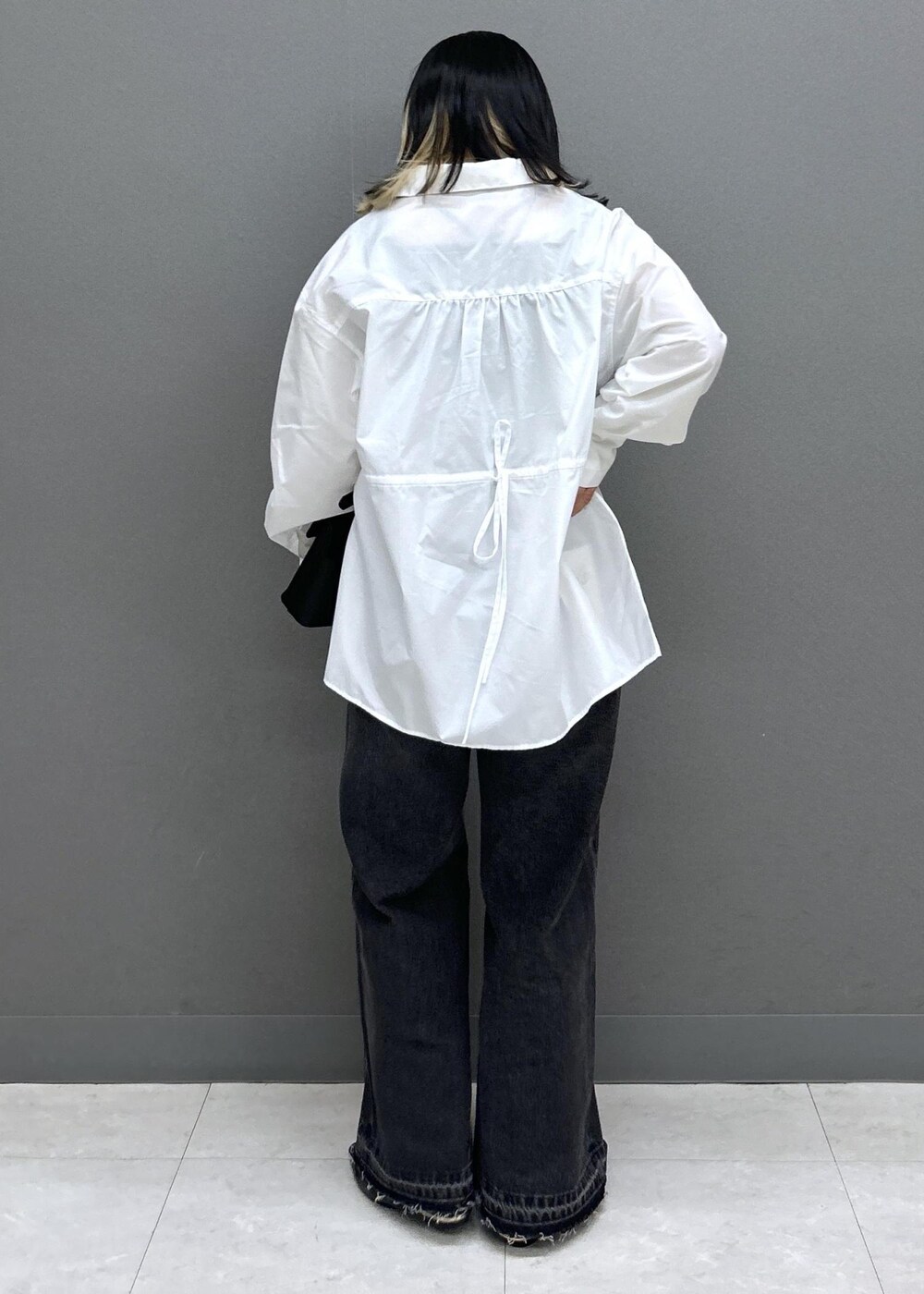 ブラック系のショルダーバッグ、ブラック系のパンプス、ブラック系のデニムパンツを着用したレディースの春コーディネートの6枚目の写真