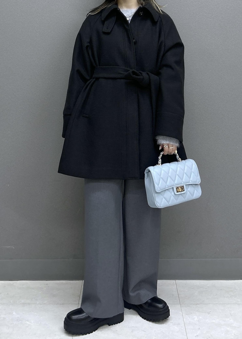 グレー系のスラックス、ブラック系のブーツ、ブラック系のチェスターコートを着用したレディースの秋コーディネートの2枚目の写真