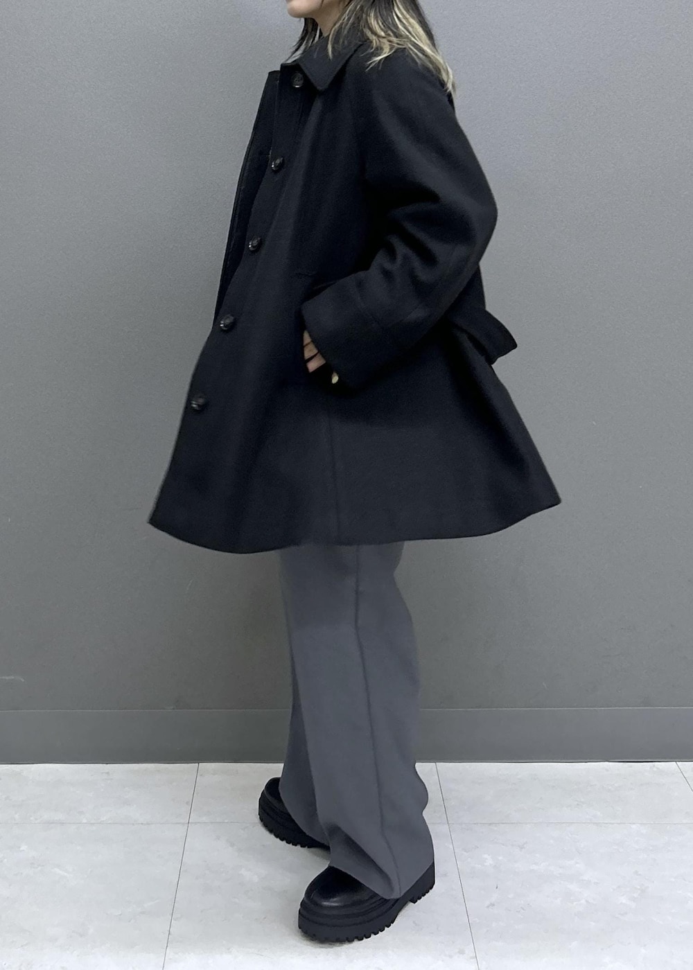 グレー系のスラックス、ブラック系のブーツ、ブラック系のチェスターコートを着用したレディースの秋コーディネートの6枚目の写真