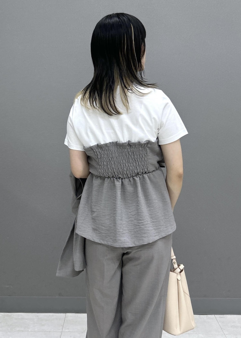 ベージュ系のショルダーバッグ、ホワイト系のパンプス、グレー系のTシャツ/カットソーを着用したレディースの夏コーディネートの5枚目の写真