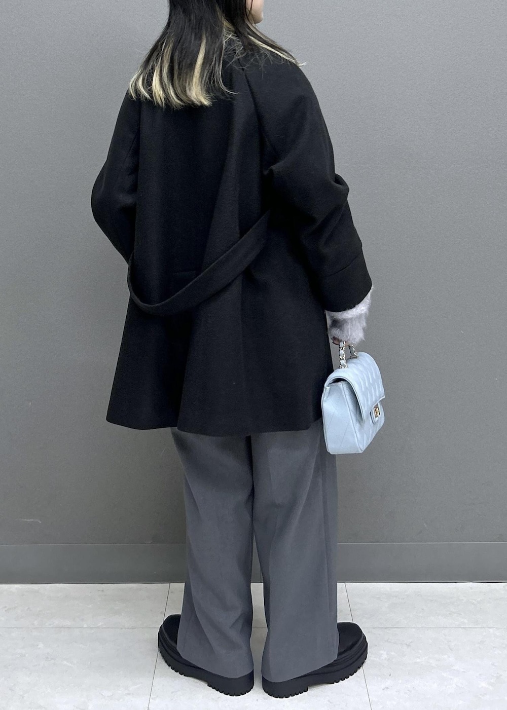 グレー系のスラックス、ブラック系のブーツ、ブラック系のチェスターコートを着用したレディースの秋コーディネートの7枚目の写真