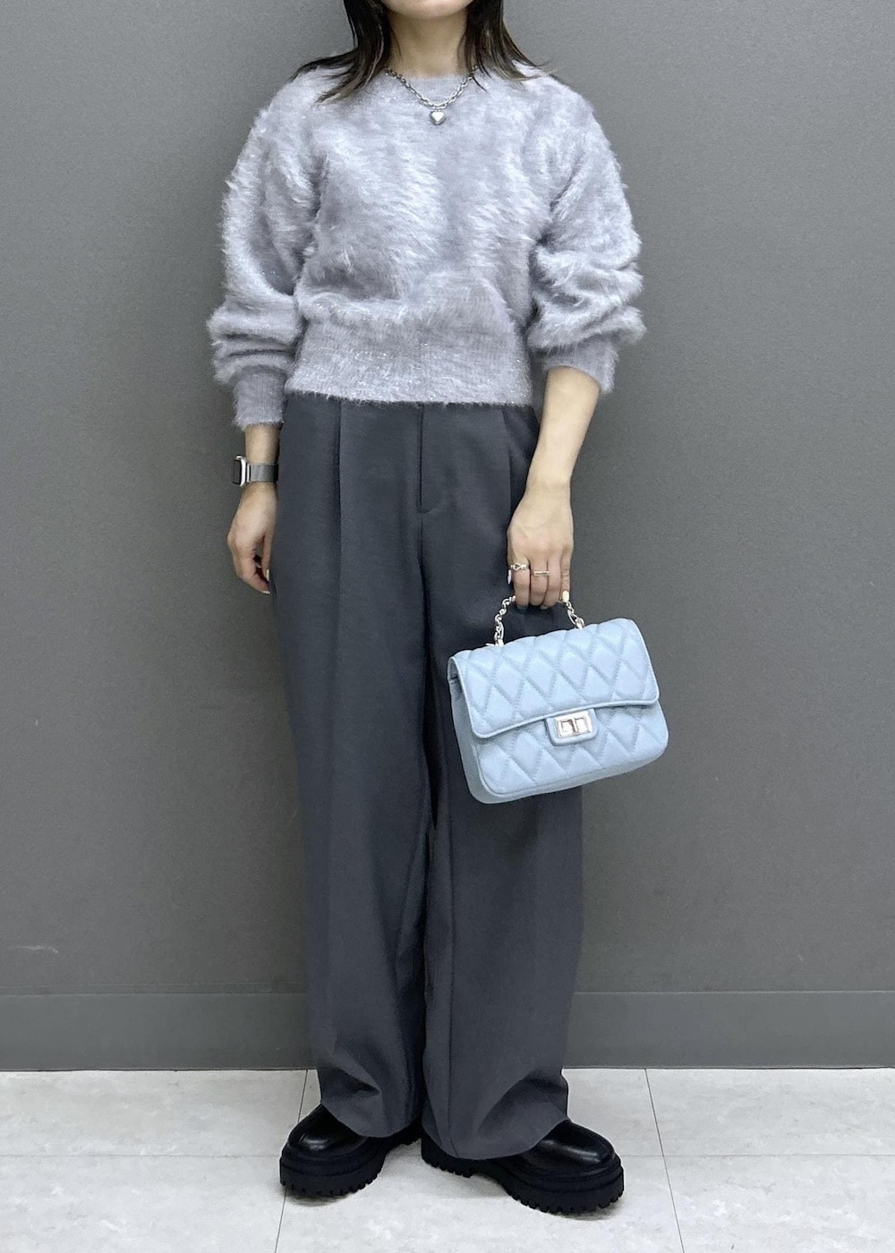 グレー系のスラックス、ブラック系のブーツ、ブラック系のチェスターコートを着用したレディースの秋コーディネートの9枚目の写真