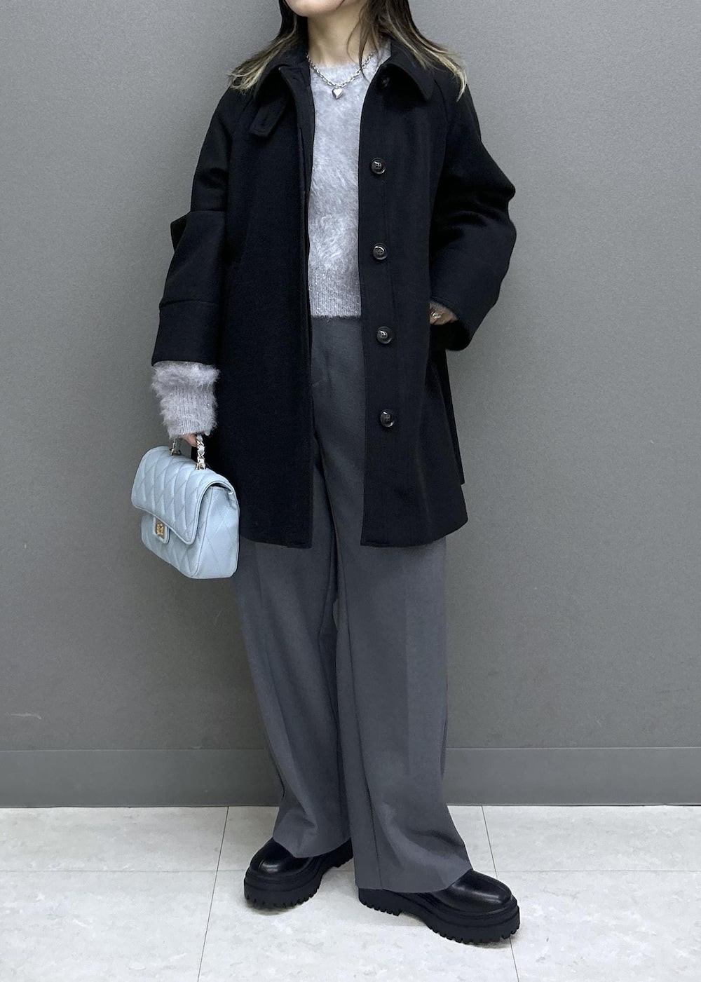 グレー系のスラックス、ブラック系のブーツ、ブラック系のチェスターコートを着用したレディースの秋コーディネートの5枚目の写真