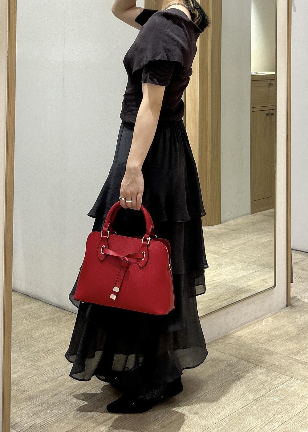 ブラック系のパンプス、レッド系のボストンバッグ、グレー系のニット/セーターを着用したレディースの秋コーディネートの3枚目の写真