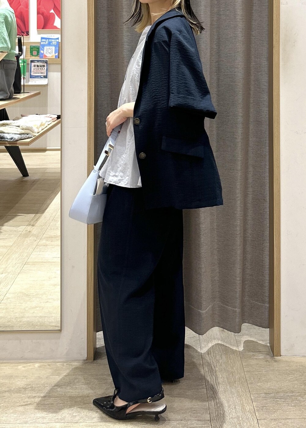 ブルー系のハンドバッグ、ブラック系のパンプス、ブラック系のキャミソールを着用したレディースの夏コーディネートの6枚目の写真