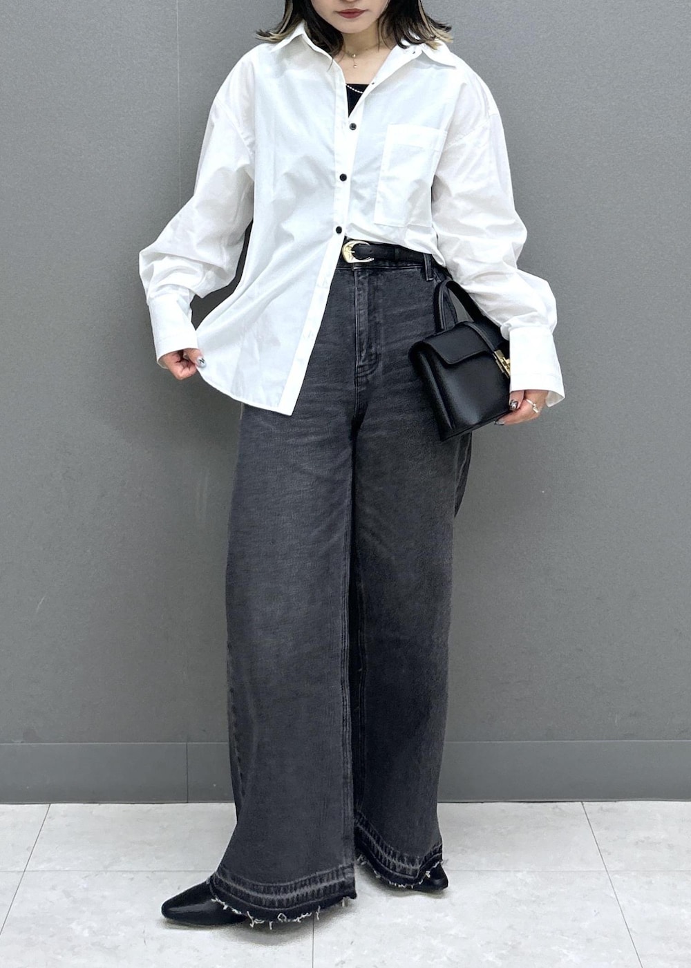 ブラック系のショルダーバッグ、ブラック系のパンプス、ブラック系のデニムパンツを着用したレディースの春コーディネートの3枚目の写真