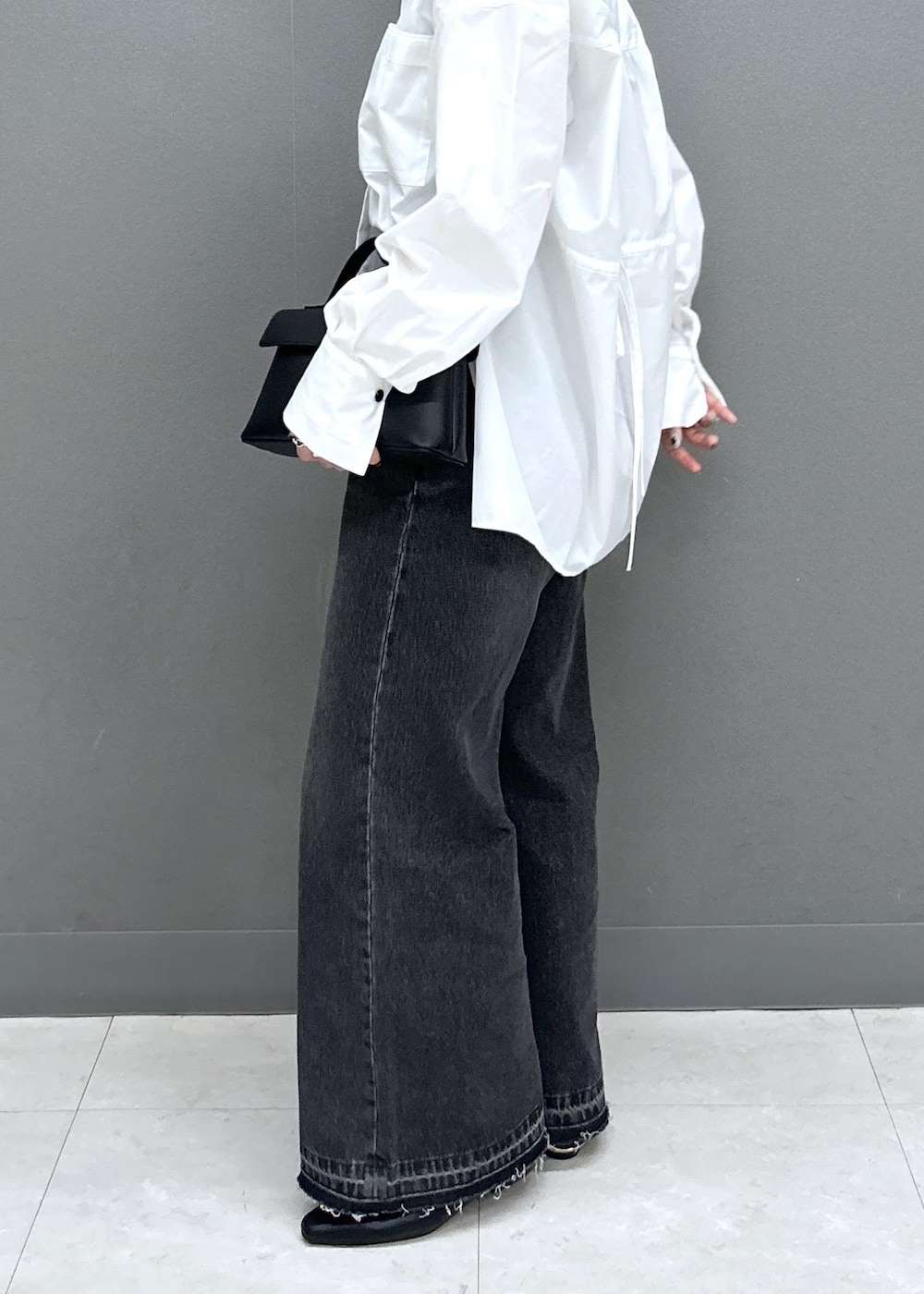 ブラック系のショルダーバッグ、ブラック系のパンプス、ブラック系のデニムパンツを着用したレディースの春コーディネートの5枚目の写真