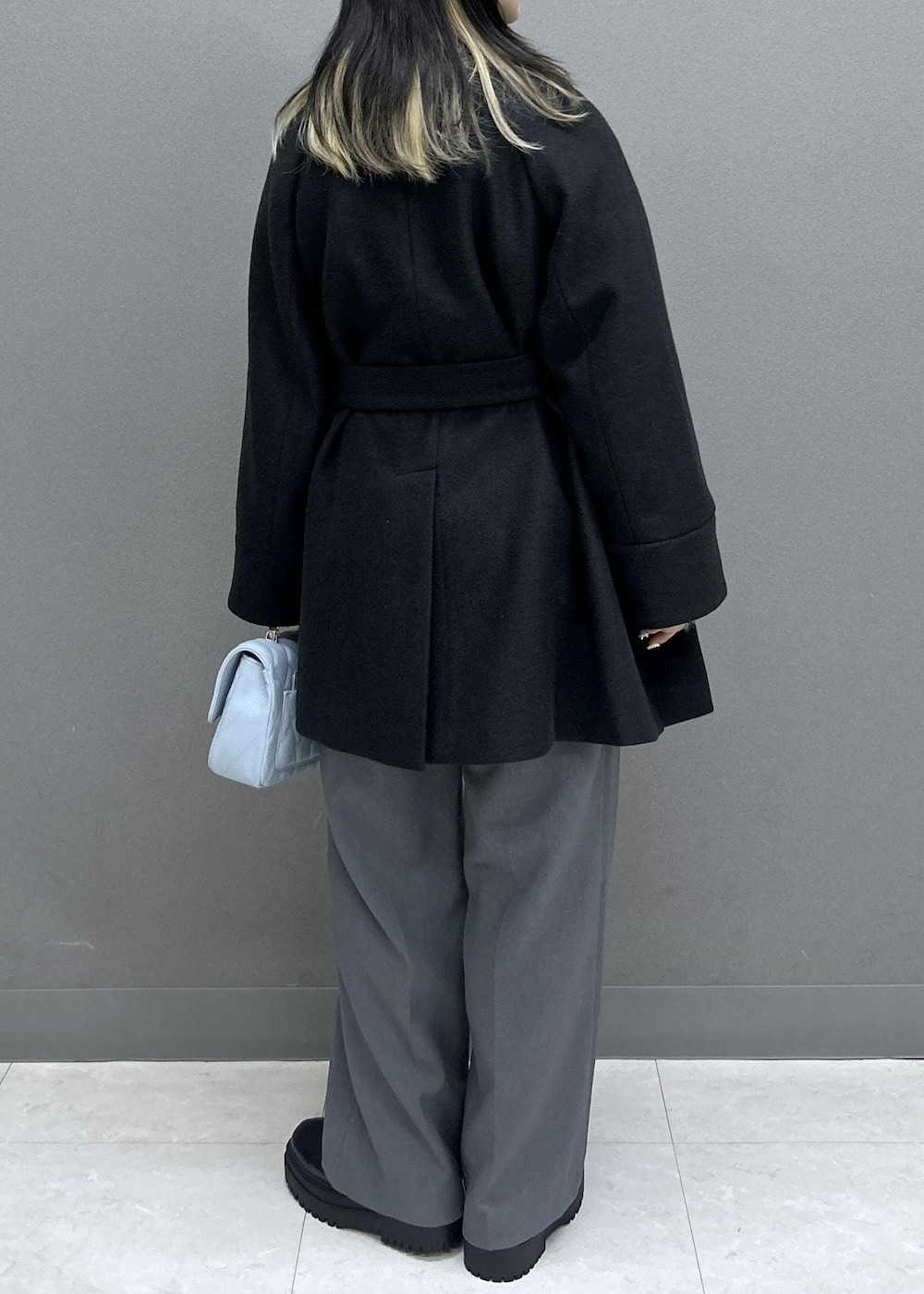 グレー系のスラックス、ブラック系のブーツ、ブラック系のチェスターコートを着用したレディースの秋コーディネートの4枚目の写真