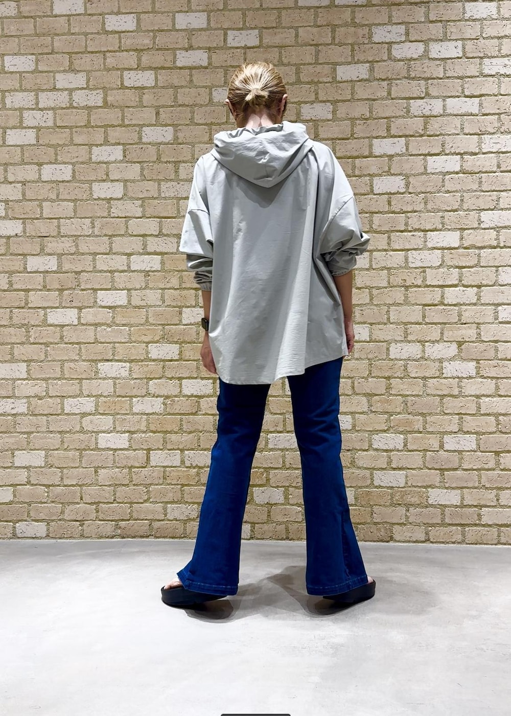 ブラック系のサンダル、グリーン系のパーカー、ブルー系のデニムパンツを着用したレディースの夏コーディネートの3枚目の写真