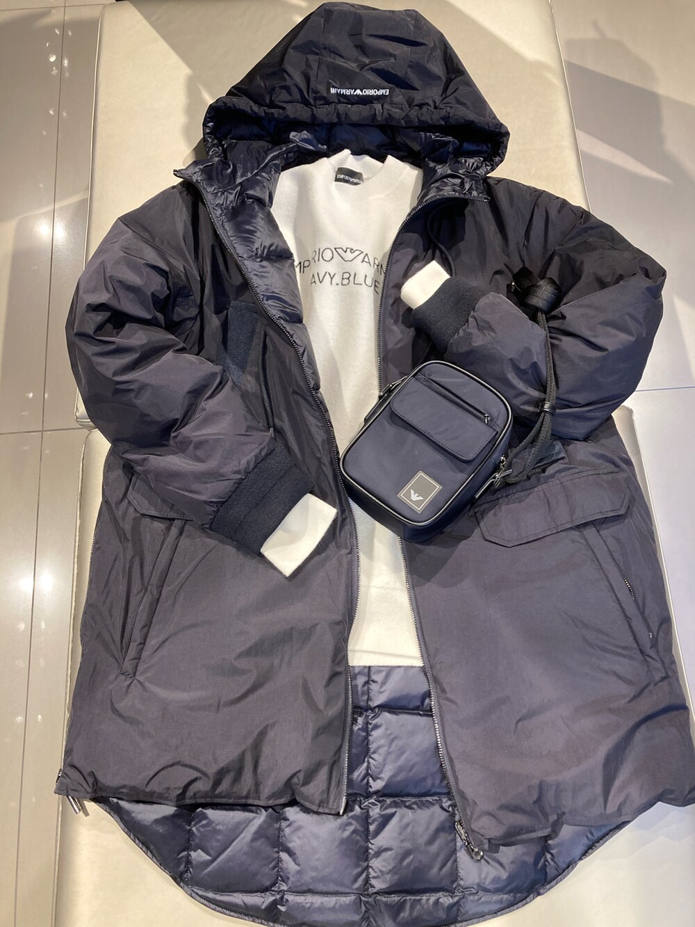 ブルー系のショルダーバッグ、ブルー系のダウンジャケット/コート、ブラック系のブーツを着用したレディースの秋コーディネートの2枚目の写真