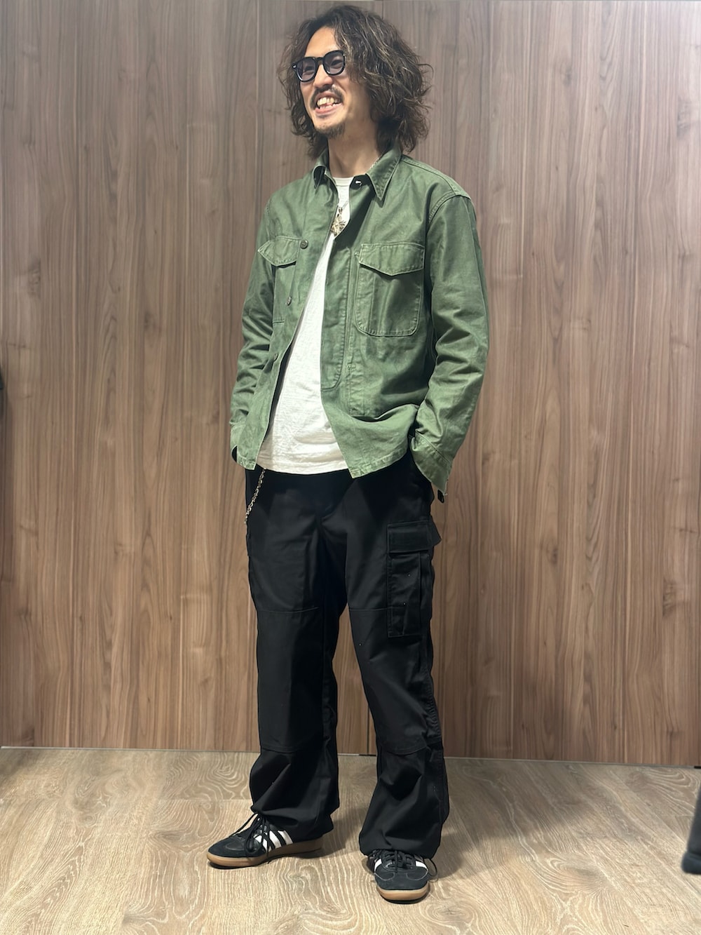 グリーン系のミリタリージャケット、ブラック系のカーゴパンツ、ブラック系のスニーカーを着用したメンズの冬コーディネートの2枚目の写真