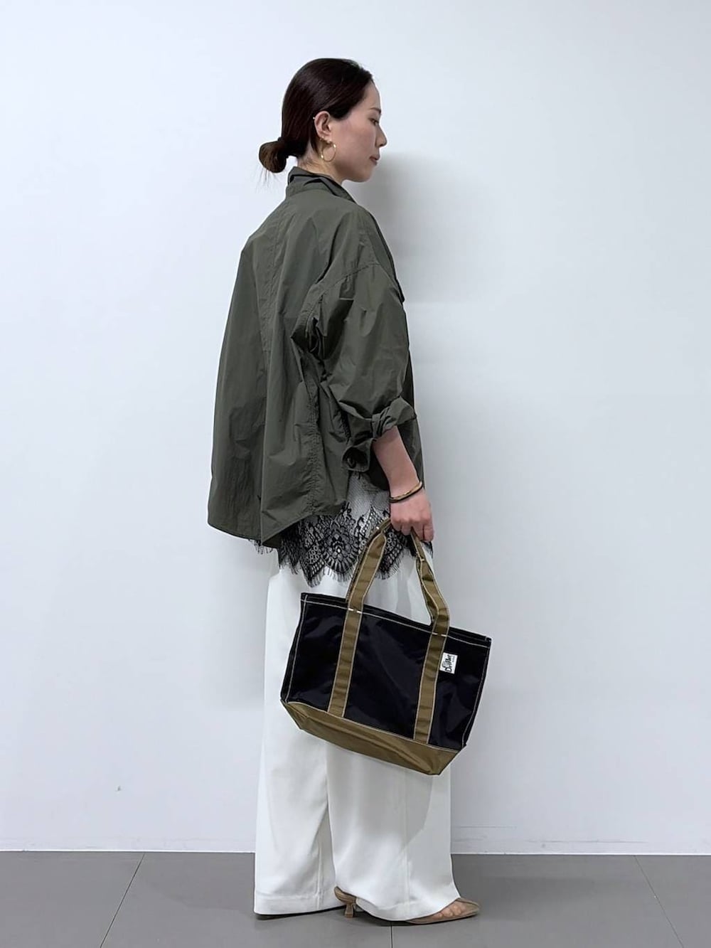 ホワイト系のスラックス、グリーン系のシャツ/ブラウス、ベージュ系のパンプスを着用したレディースの春コーディネートの2枚目の写真