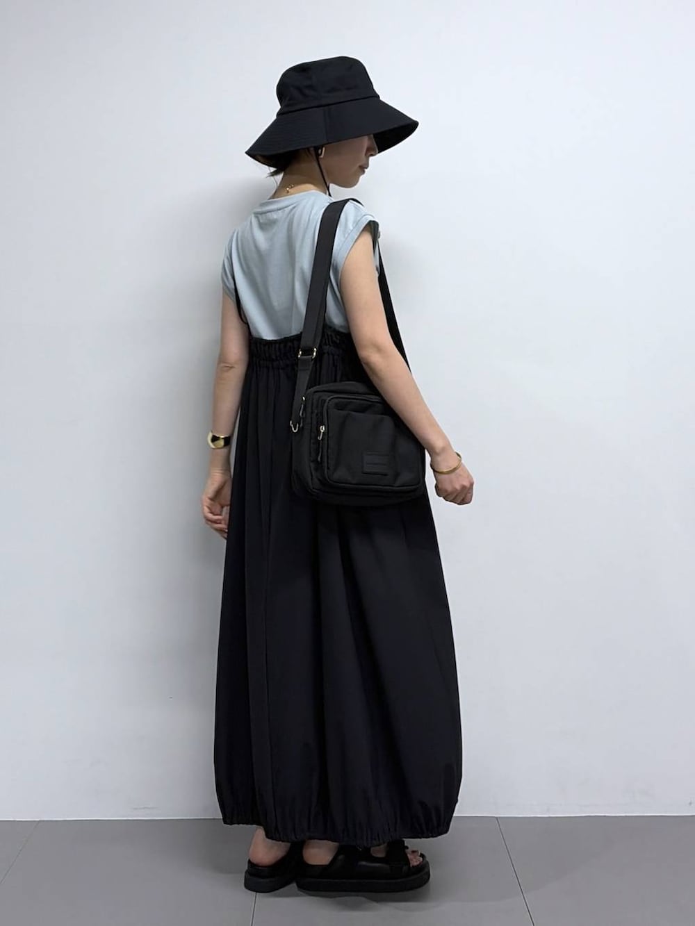 グリーン系のTシャツ/カットソー、ブラック系のサンダル、ブラック系のハットを着用したレディースの春コーディネートの2枚目の写真