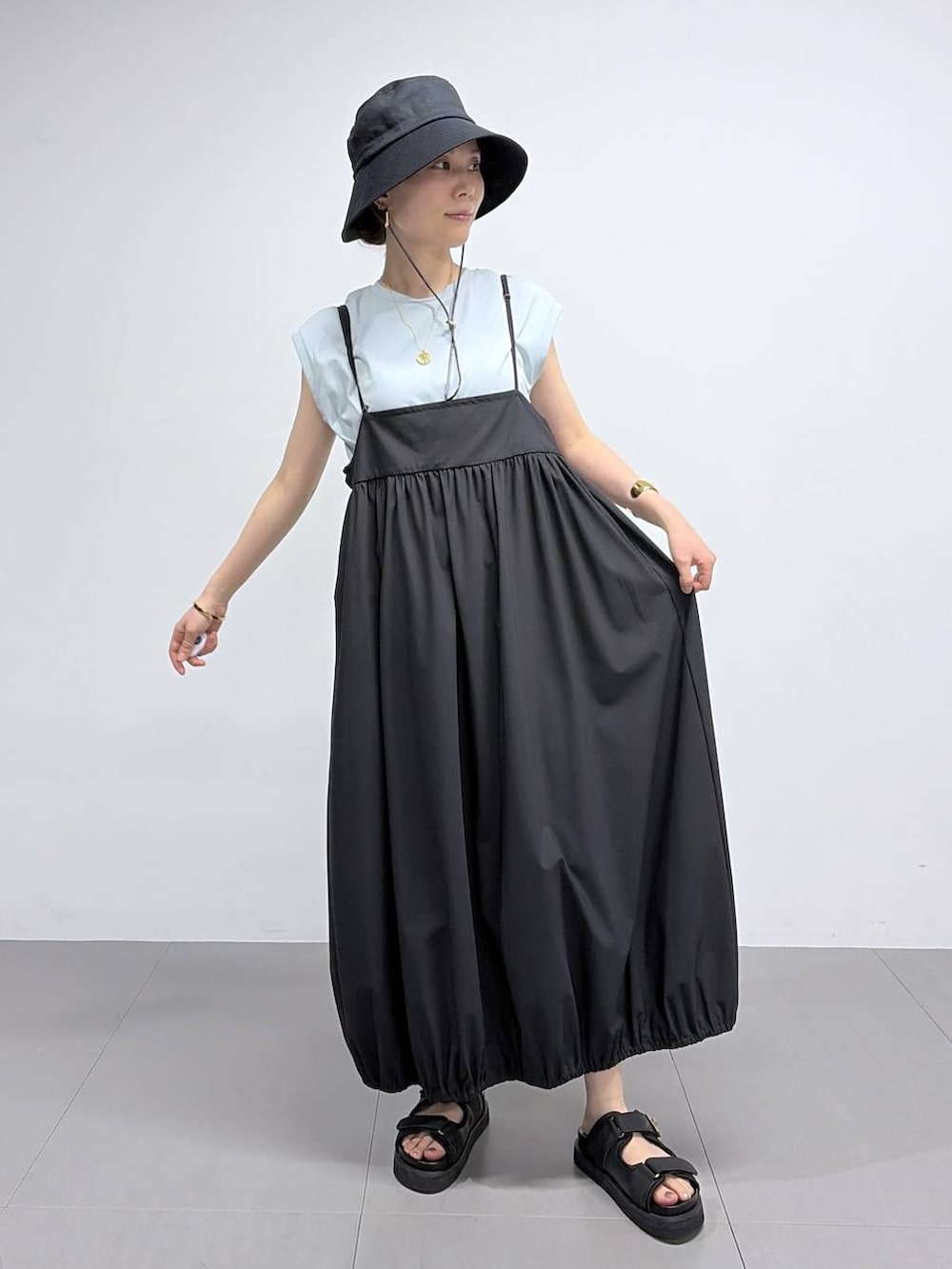 グリーン系のTシャツ/カットソー、ブラック系のサンダル、ブラック系のハットを着用したレディースの春コーディネートの4枚目の写真