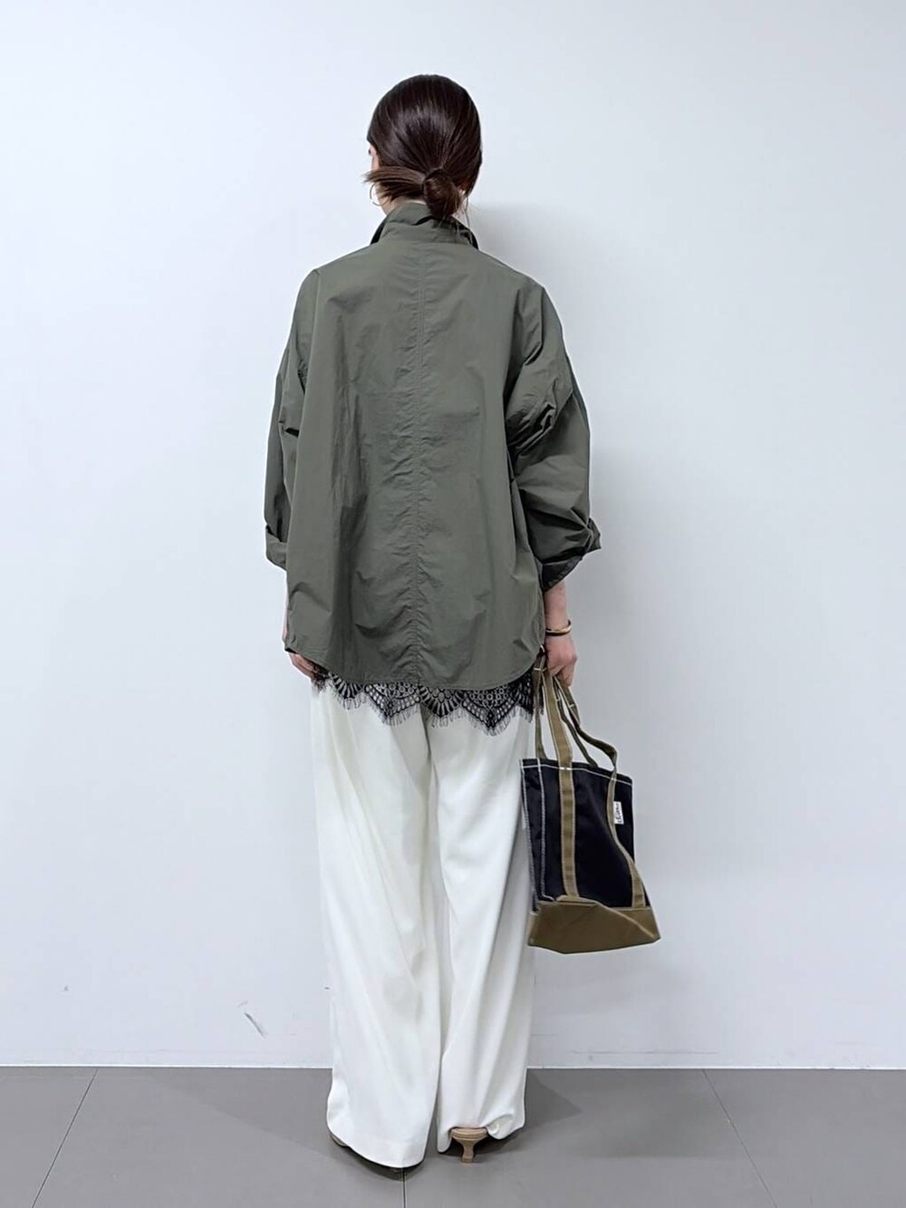 ホワイト系のスラックス、グリーン系のシャツ/ブラウス、ベージュ系のパンプスを着用したレディースの春コーディネートの3枚目の写真