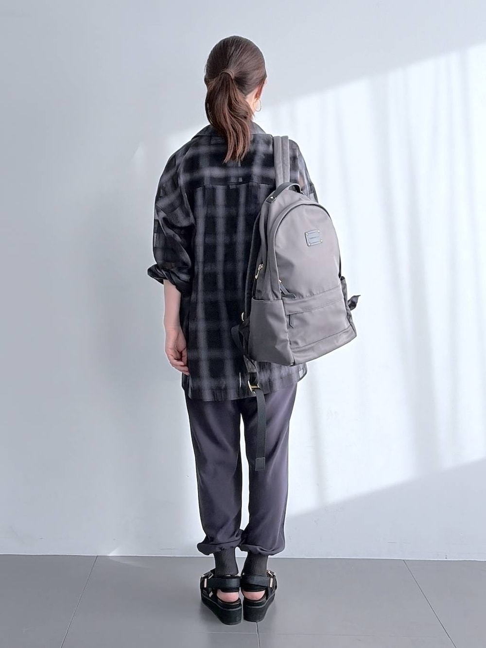 グレー系のバックパック/リュック、ブラック系のサンダル、ブラック系のシャツ/ブラウスを着用したレディースの夏コーディネートの3枚目の写真