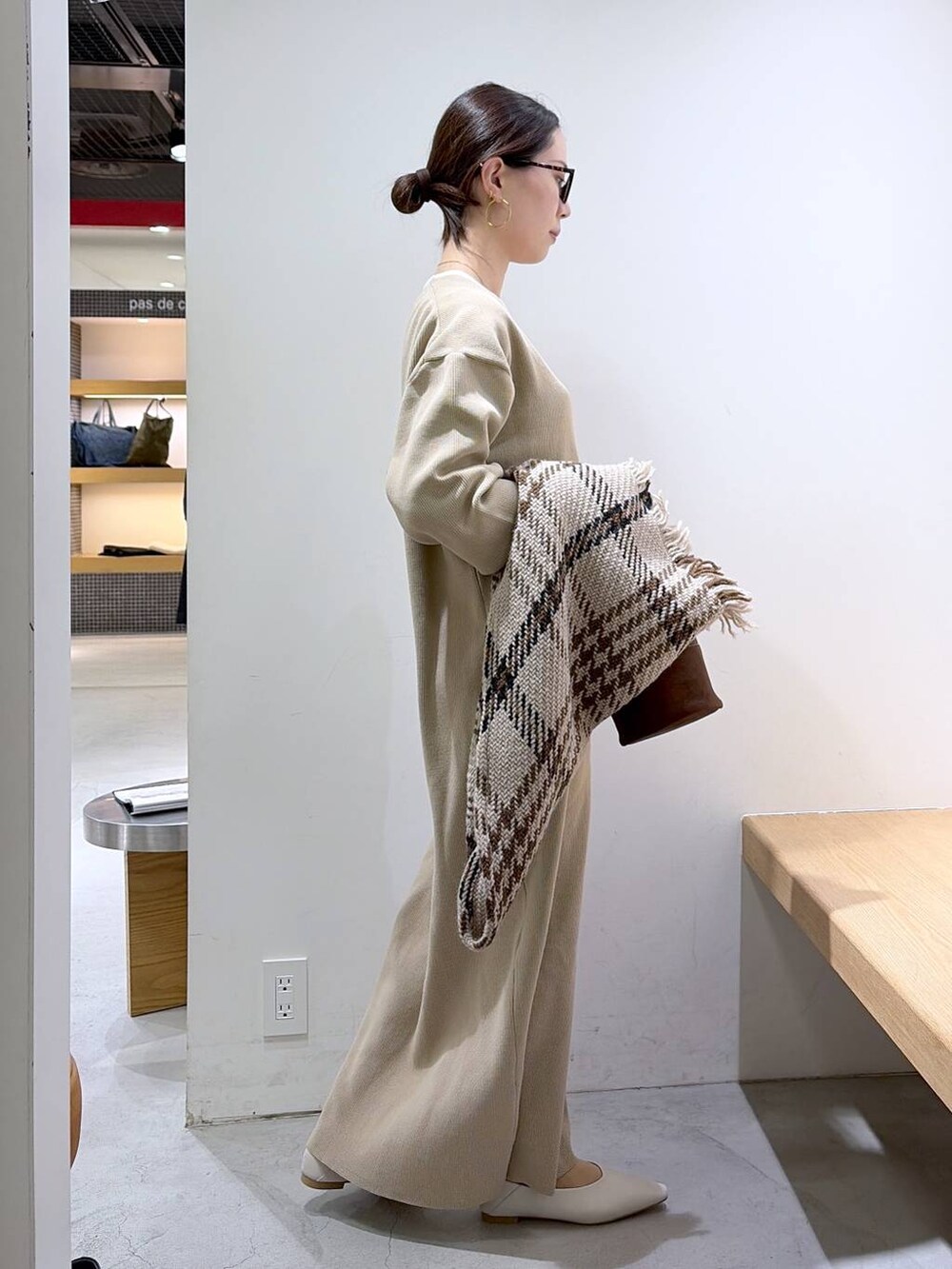 ホワイト系のニット/セーター、ベージュ系のワンピース、ブラウン系のハンドバッグを着用したレディースの冬コーディネートの2枚目の写真