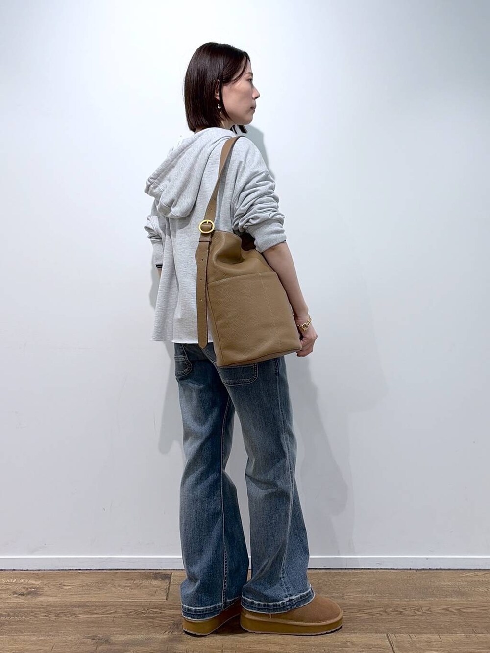 イエロー系のトートバッグ、イエロー系のその他シューズ、ブルー系のデニムパンツを着用したレディースの秋コーディネートの2枚目の写真