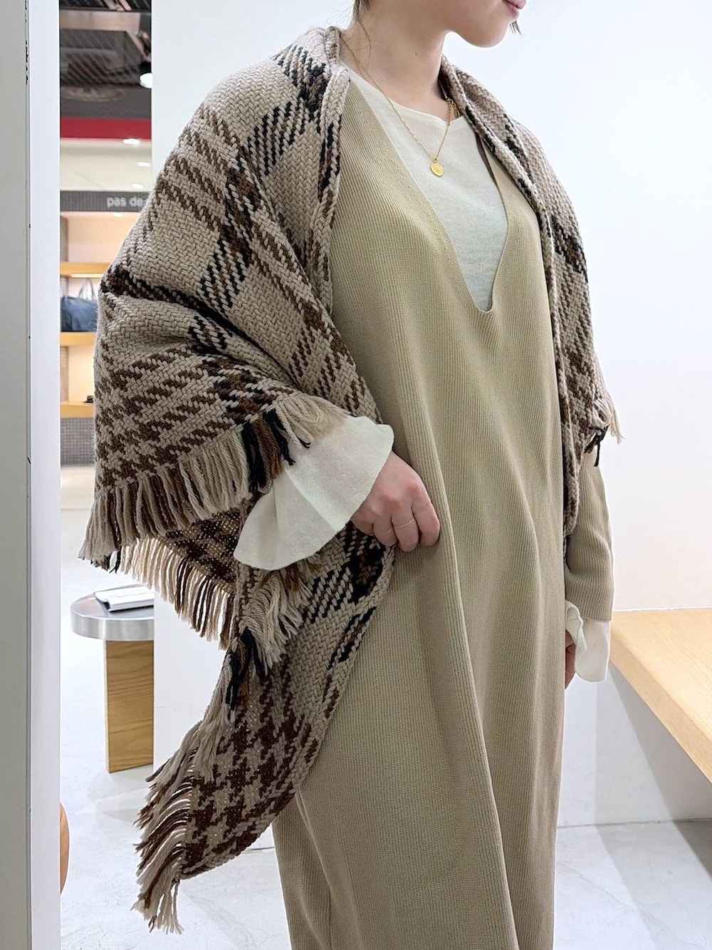 ホワイト系のニット/セーター、ベージュ系のワンピース、ブラウン系のハンドバッグを着用したレディースの冬コーディネートの7枚目の写真