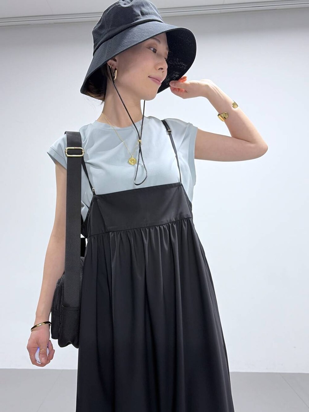 グリーン系のTシャツ/カットソー、ブラック系のサンダル、ブラック系のハットを着用したレディースの春コーディネートの5枚目の写真