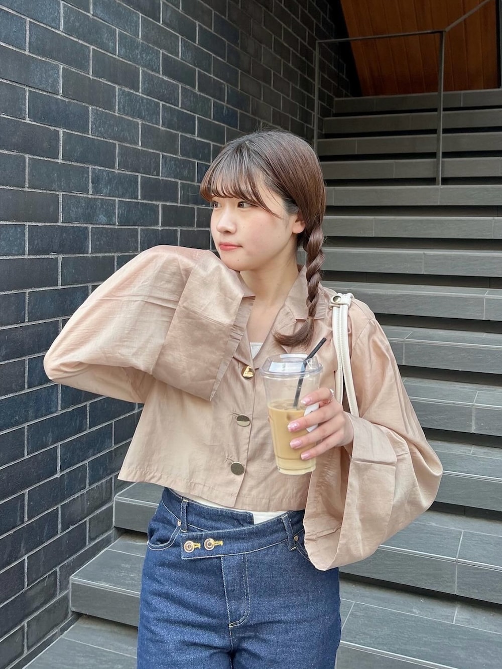 ブルー系のデニムパンツ、ホワイト系のスニーカー、ブラウン系のジャケット/アウターを着用したレディースの春コーディネートの2枚目の写真