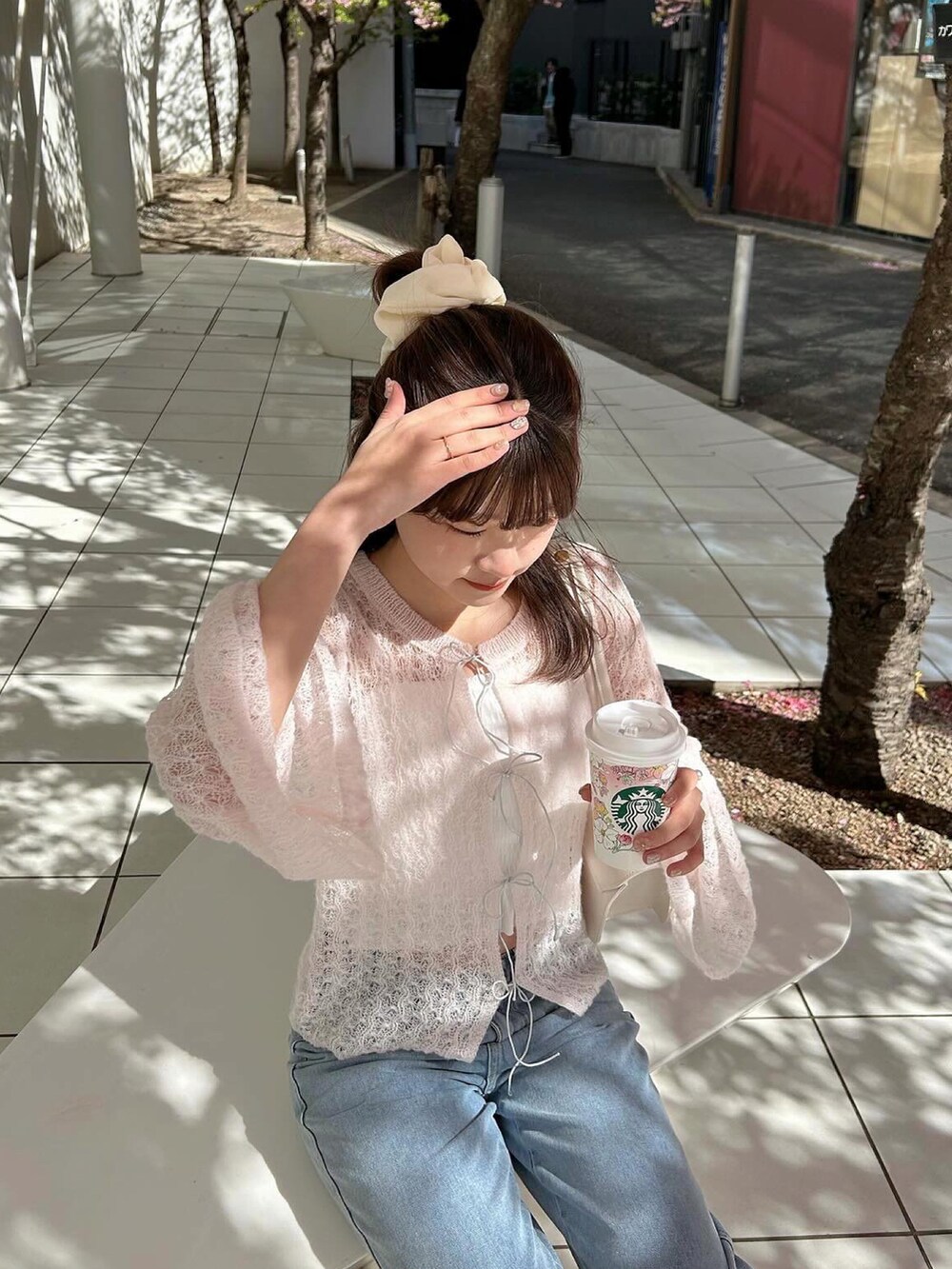 ブルー系のデニムパンツ、ピンク系のニット/セーター、ホワイト系のスニーカーを着用したレディースの春コーディネートの2枚目の写真