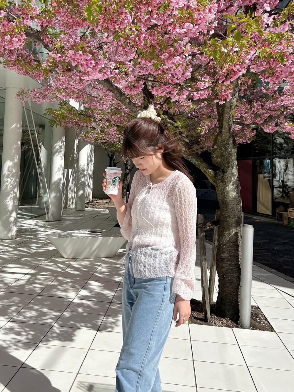 ブルー系のデニムパンツ、ピンク系のニット/セーター、ホワイト系のスニーカーを着用したレディースの春コーディネートの4枚目の写真