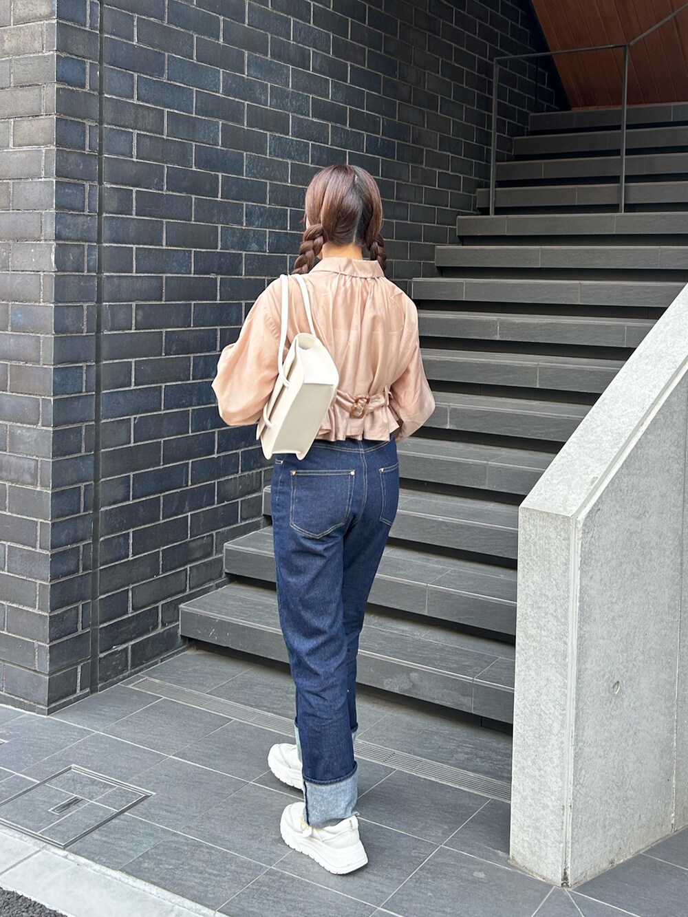 ブルー系のデニムパンツ、ホワイト系のスニーカー、ブラウン系のジャケット/アウターを着用したレディースの春コーディネートの4枚目の写真