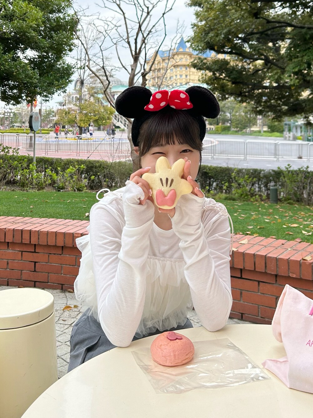 ホワイト系のスニーカー、ホワイト系のトップス、ピンク系のトートバッグを着用したレディースの春コーディネートの2枚目の写真