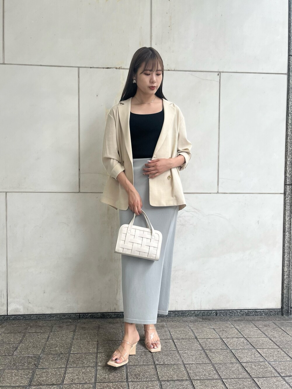 ブルー系のスカート、ホワイト系のショルダーバッグ、ベージュ系のテーラードジャケットを着用したレディースの夏コーディネートの2枚目の写真