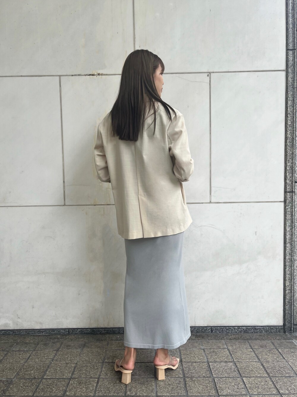 ブルー系のスカート、ホワイト系のショルダーバッグ、ベージュ系のテーラードジャケットを着用したレディースの夏コーディネートの4枚目の写真