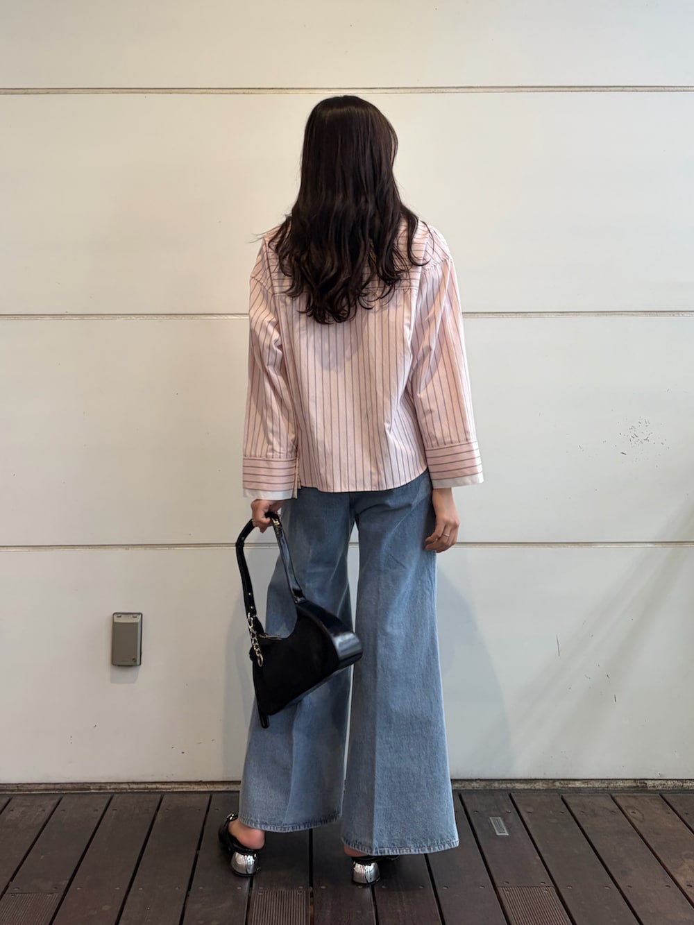 ピンク系のシャツ/ブラウス、ブルー系のデニムパンツ、ブラック系のハンドバッグを着用したレディースの春コーディネートの2枚目の写真