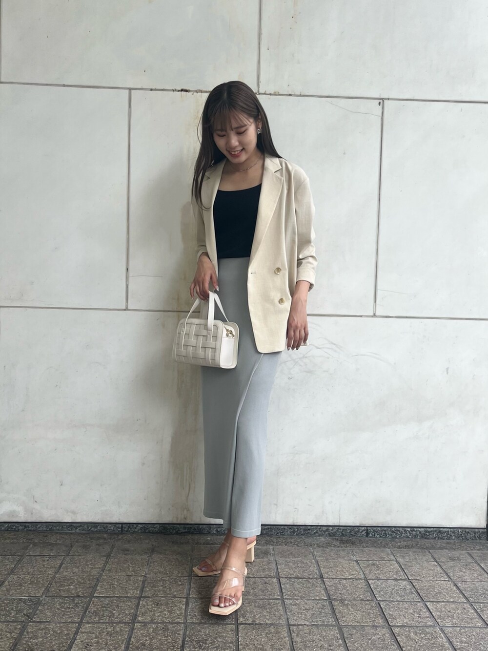 ブルー系のスカート、ホワイト系のショルダーバッグ、ベージュ系のテーラードジャケットを着用したレディースの夏コーディネートの3枚目の写真