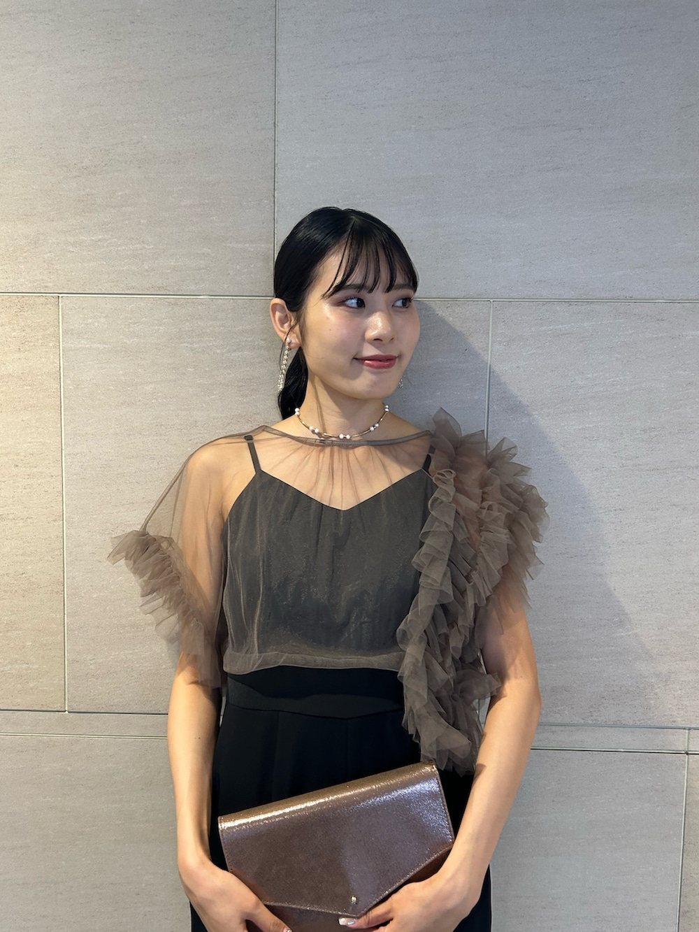 ゴールド系のクラッチバッグ、ブラック系のパンプス、その他のパンツドレスを着用したレディースの秋コーディネートの6枚目の写真