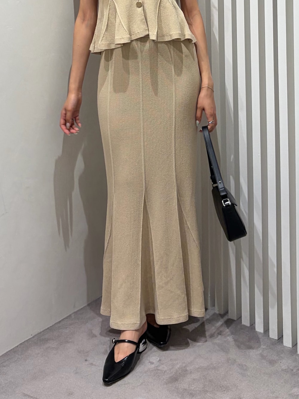 ベージュ系のニット/セーター、ベージュ系のスカート、ブラック系のハンドバッグを着用したレディースの夏コーディネートの5枚目の写真