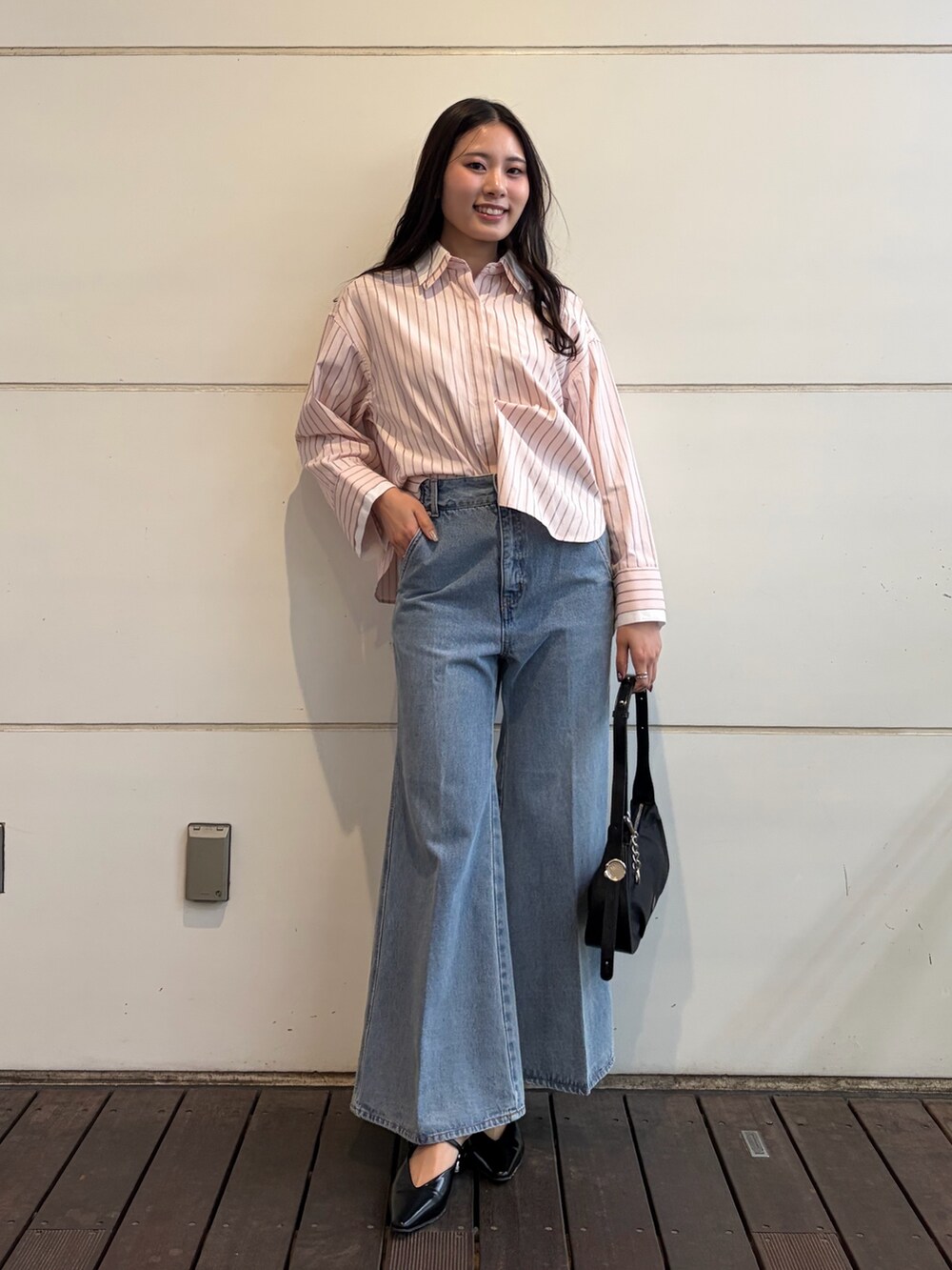 ピンク系のシャツ/ブラウス、ブルー系のデニムパンツ、ブラック系のハンドバッグを着用したレディースの春コーディネートの3枚目の写真