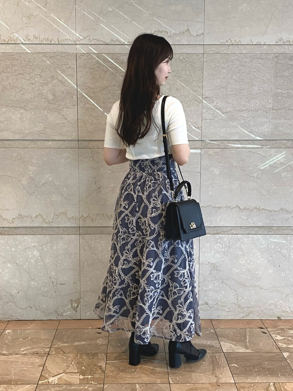 グレー系のスカート、ホワイト系のニット/セーター、ブラック系のブーツを着用したレディースの夏コーディネートの3枚目の写真