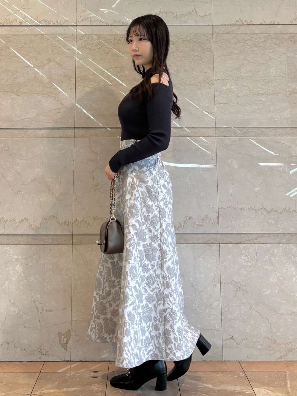 ブラウン系のハンドバッグ、ブラック系のブーツ、グレー系のニット/セーターを着用したレディースの冬コーディネートの3枚目の写真