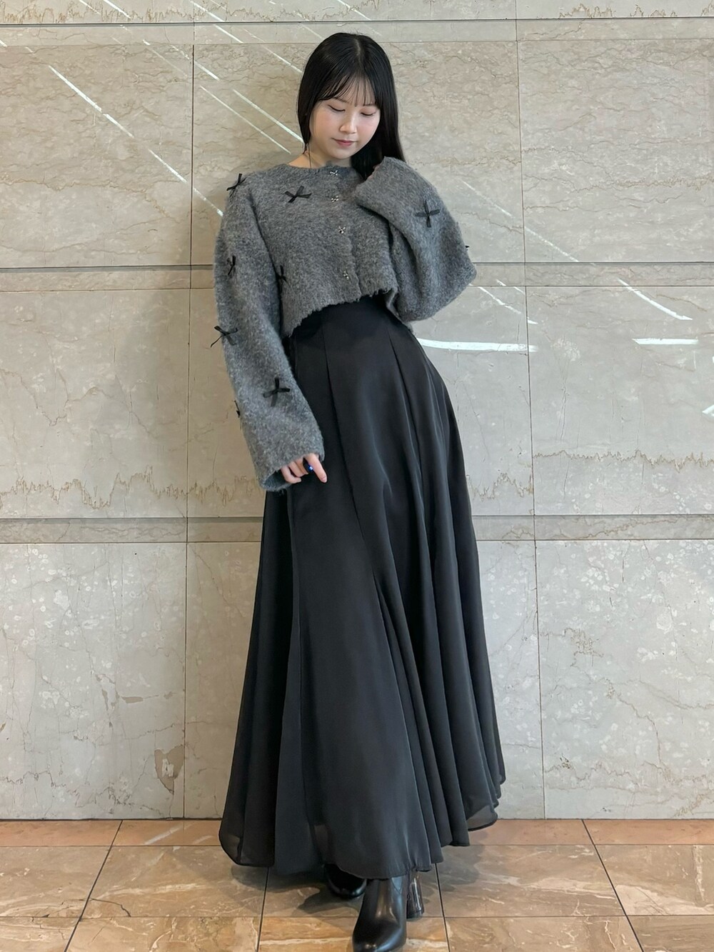 ブラック系のスカート、ブラック系のブーツ、グレー系のカーディガン/ボレロを着用したレディースの冬コーディネートの2枚目の写真