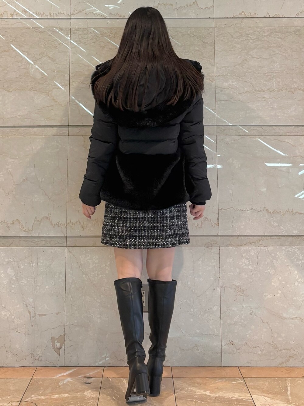 ブラック系のスカート、ブラウン系のブーツ、ブラック系のテーラードジャケットを着用したレディースの冬コーディネートの2枚目の写真