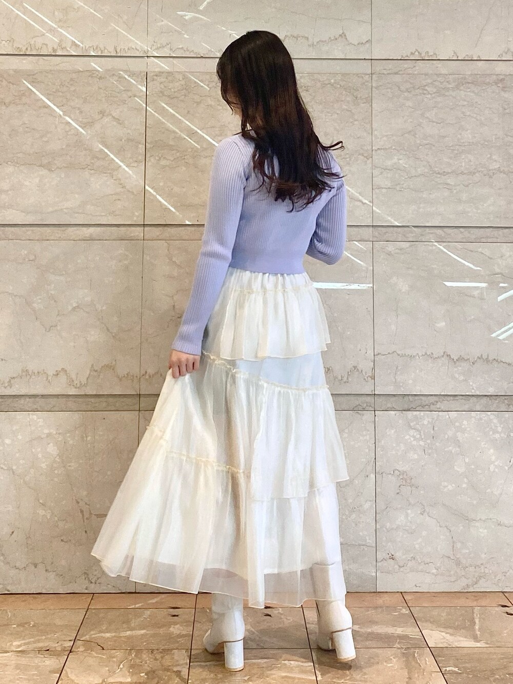 ブルー系のカーディガン/ボレロ、ホワイト系のスカート、ホワイト系のブーツを着用したレディースの冬コーディネートの2枚目の写真