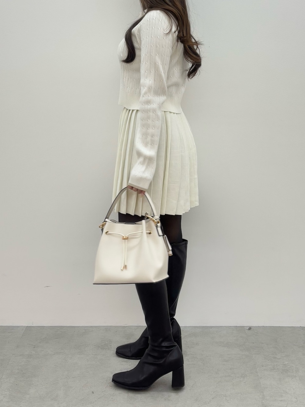 ブラウン系のブーツ、ホワイト系のショルダーバッグ、ホワイト系のワンピースを着用したレディースの冬コーディネートの3枚目の写真