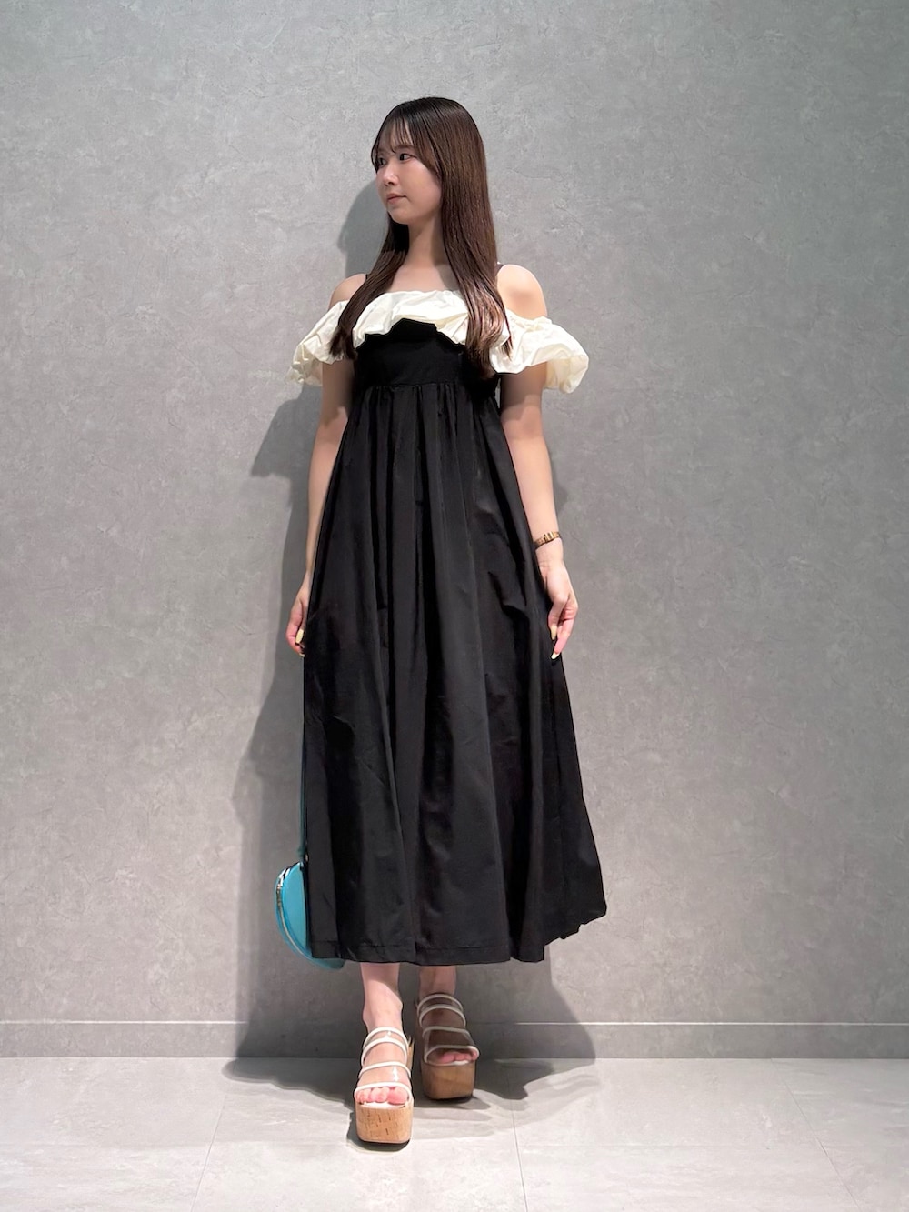ブラック系のワンピース、グリーン系のショルダーバッグ、その他のサンダルを着用したレディースの夏コーディネートの2枚目の写真