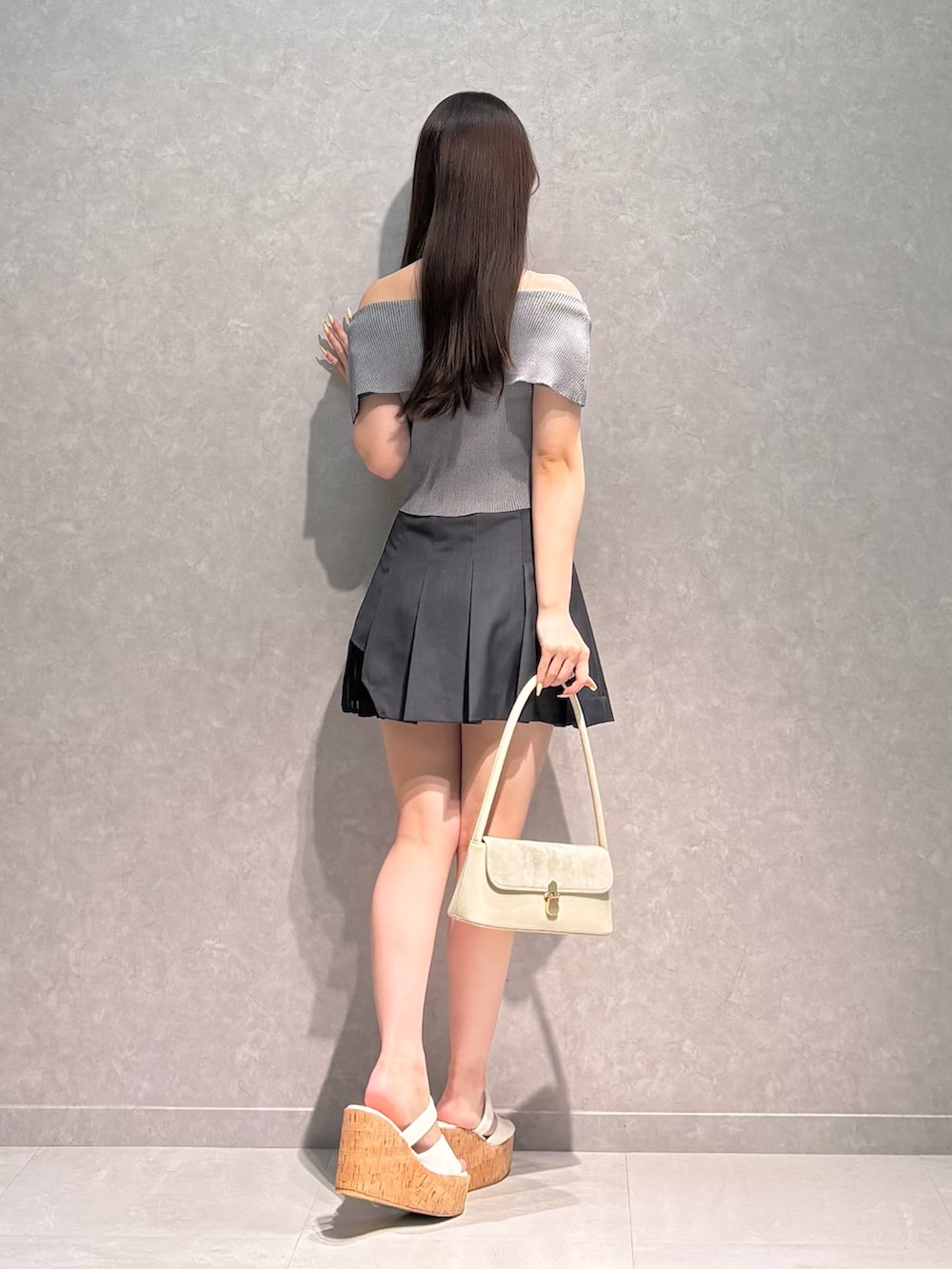グレー系のスカート、グレー系のニット/セーター、ホワイト系のハンドバッグを着用したレディースの夏コーディネートの5枚目の写真
